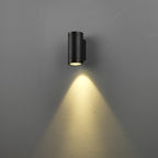 Black outdoor wall light fixture on a gray wall with a soft glow.