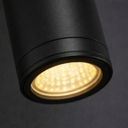 Black cylindrical light fixture with a glowing interior on a dark background