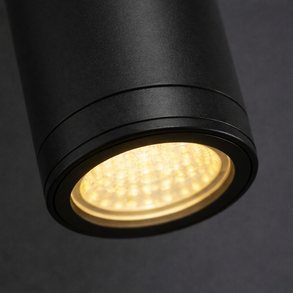 Black cylindrical light fixture with a glowing interior on a dark background