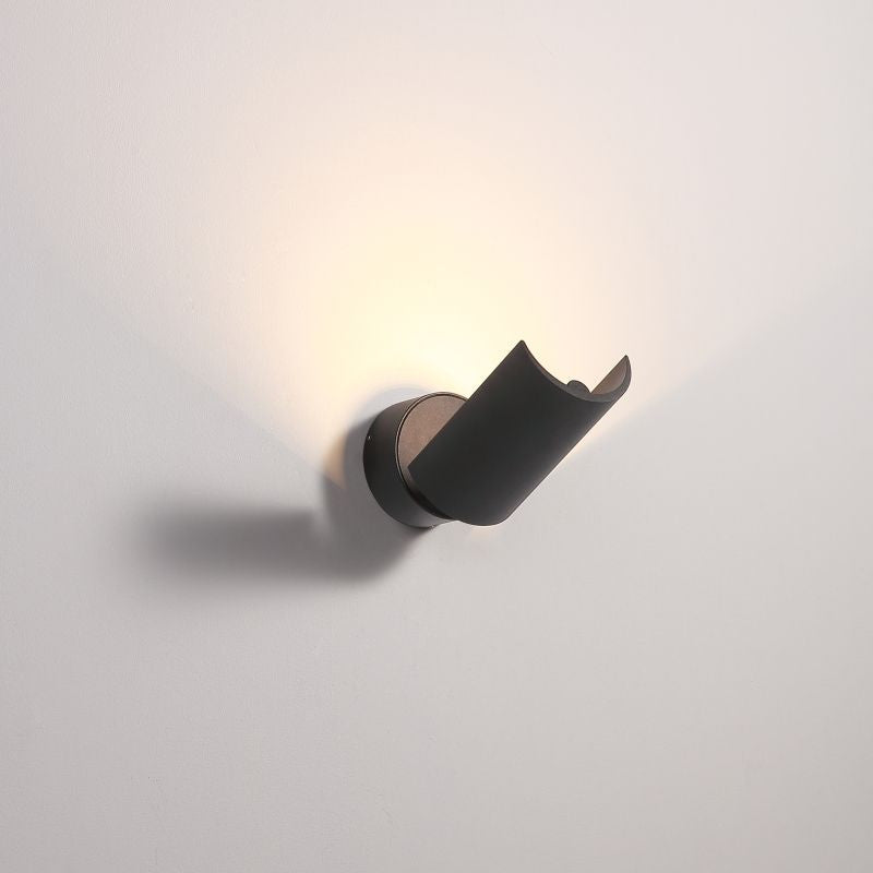 Black half cylinder up light wall light fixture on a pale grey background.